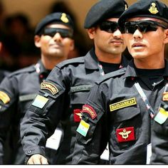 three men in uniform are walking together with their hands on their hips and one is wearing sunglasses