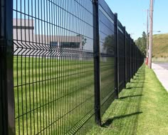 a long black fence is next to the road and grass on the side of the road