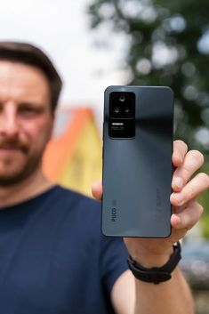 a man holding up his new cell phone in front of the camera with one hand