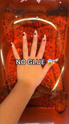 a person's hand with black and white nail polish on it, in front of an orange background that says no glue