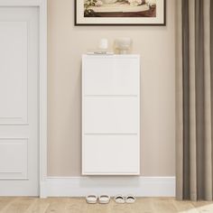 a white cabinet sitting in the corner of a room next to a pair of shoes