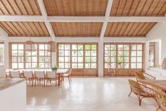 a large open living room and dining area with wood accents on the ceiling, along with white walls and flooring