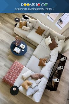 an aerial view of a living room with white couches and pillows on the floor