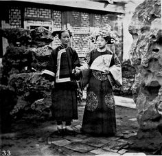 an old photo of two women standing next to each other in front of some rocks