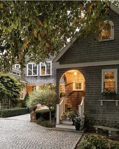 a house that is sitting on the side of a road with trees in front of it