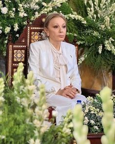 a woman sitting in a chair surrounded by flowers