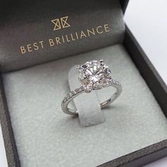 a diamond ring in a box on a white surface with the lid open to show it's center stone