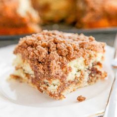 a close up of a piece of cake on a plate with a fork and cupcake in the background