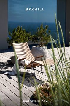 A brown garden sun lounger set on a wooden deck outdoor setting beside potted plants