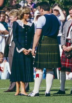 two men in kilts standing next to each other on a field with people watching