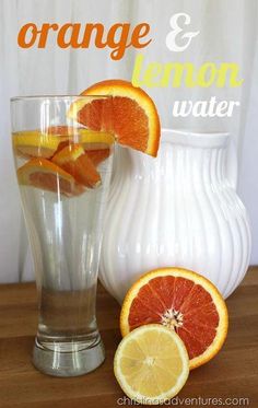 an orange and lemon water is in a glass next to some sliced up oranges