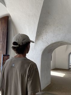 a man standing in front of a white wall with arched doorways on both sides