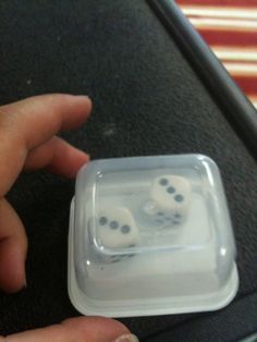 two dices are in a plastic container on the table and someone is holding one