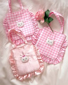 three pink and white bags with teddy bear appliques on them, one is holding a flower