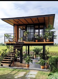 a small house with plants on the porch and stairs leading up to the second floor