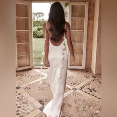 a woman in a white dress is walking through an open door with her back to the camera