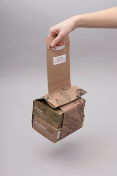 a person holding a brown paper bag in it's right hand and reaching for the box