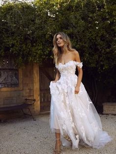 a woman in a white dress is standing outside