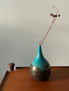 a blue vase sitting on top of a wooden table next to a small potted plant