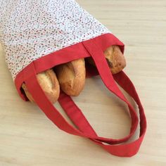 two baguettes are sitting in the middle of a red bag on top of a wooden floor