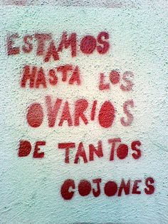 graffiti written on the side of a building in red and white writing reads estamos hasta los ovarios de tanos gones