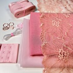 some pink items are laying out on a white table with scissors and other things to sew