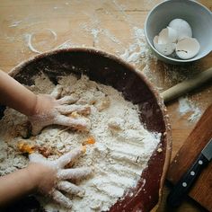 someone is mixing flour in a bowl on the table next to a cutting board and knife