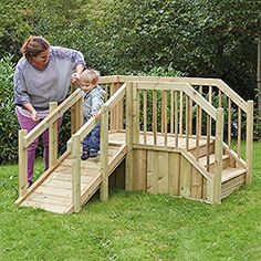 a woman standing next to a child on top of a wooden ramp