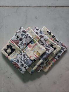 four cloths are folded on top of each other with sewing related images printed on them