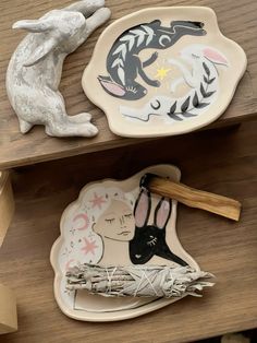 two plates with animals on them sitting on top of a wooden shelf next to other items