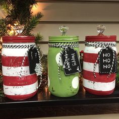 three mason jars decorated with red, white and green striped fabric are sitting on a mantle