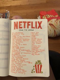 a hand holding an open book with the words netflix written in red and yellow on it