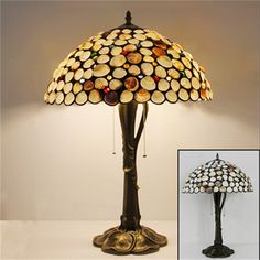 a lamp that is sitting on top of a table next to a lamp shade with chains hanging from it