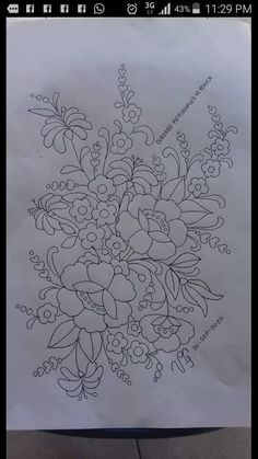 a drawing on paper with flowers and leaves in the middle, drawn by someone's hand