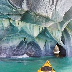 a yellow kayak is in the water next to an ice cave