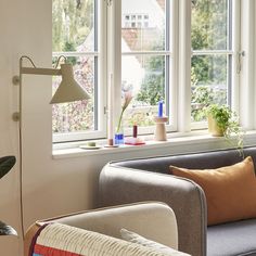 a living room filled with furniture and lots of window sill space next to a plant