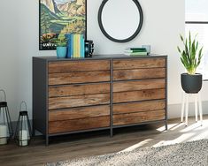 a wooden dresser sitting next to a window in a room with a painting on the wall