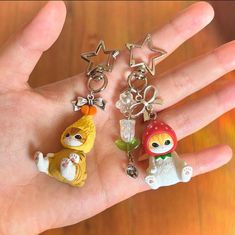 a person's hand holding three small keychains in the shape of animals