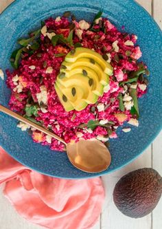 a blue bowl filled with food next to an avocado