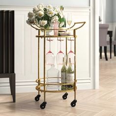 a gold bar cart with wine glasses and flowers