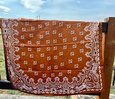 a brown and white bandana hanging on a wooden fence in front of a field