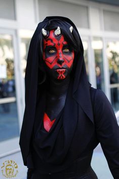 a woman in black and red makeup with horns on her head