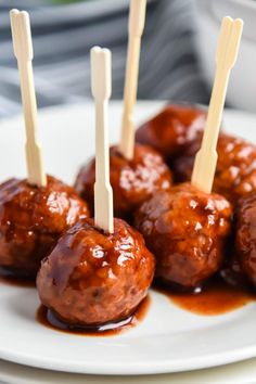 some meatballs with toothpicks in sauce on a white plate, ready to be eaten