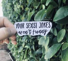 someone holding up a sticker that says your sexist jokes aren't funny