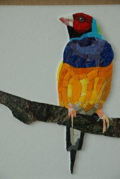 a colorful bird sitting on top of a tree branch made out of mosaics and paper