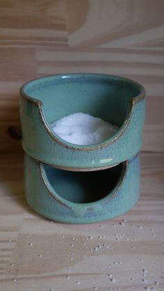 two blue bowls sitting on top of a wooden table next to each other with sugar in them