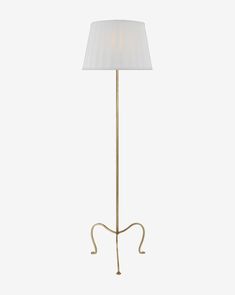 a floor lamp with a white shade on the base and a gold metal frame around it