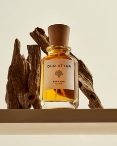 a bottle of oud attar sitting on top of a shelf next to driftwood