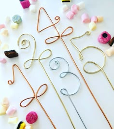 several different types of knitting needles and pins on a white surface with candy in the background