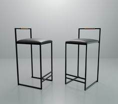 two black barstools sitting next to each other in front of a white wall